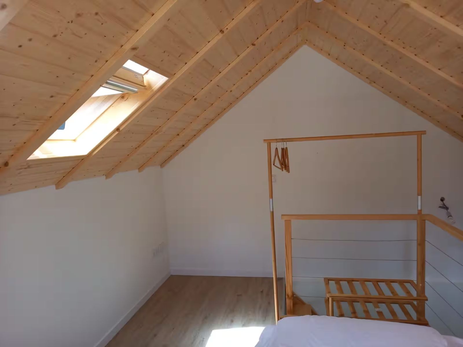 Quarto no sótão, com teto em madeira e claraboia