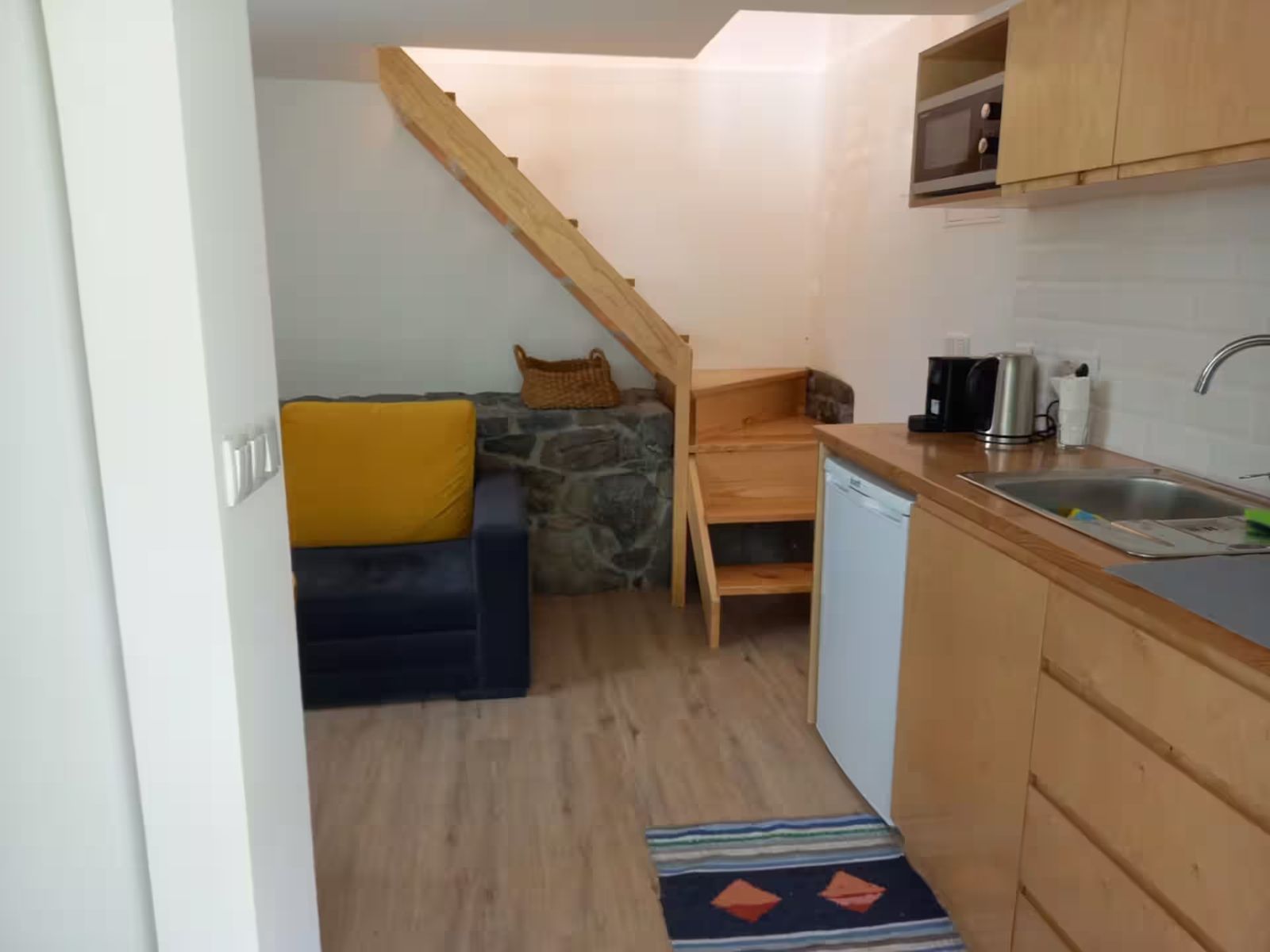 Sala e cozinha em espaço aberto, com escada para o quarto